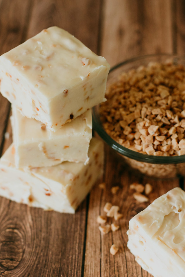 stack of health bar fudge with granola scattered on the table and in a bowl