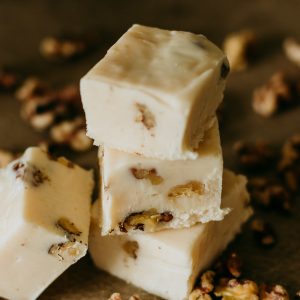vanilla walnut fudge stacked up with walnuts surrounding it
